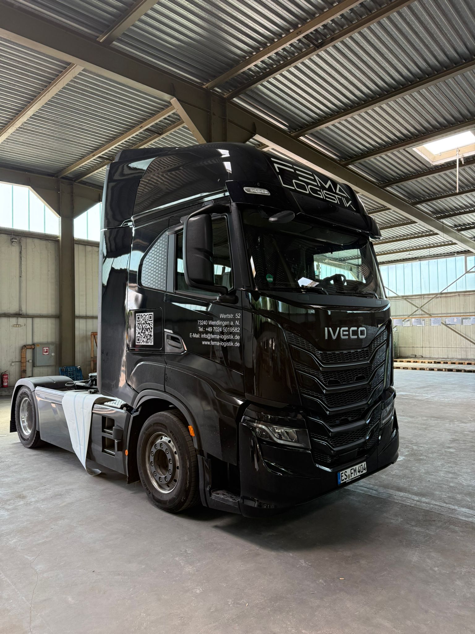 Schwarze IVECO S-Way Sattelzugmaschine der FEMA Logistik, Seitenansicht mit Kontaktdaten am Fahrerhaus